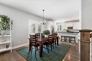 Dining space featuring sink, an inviting chandelier, and dark wood-type flooring