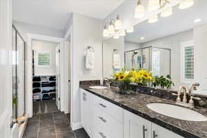 Bathroom with a shower with shower door, double vanity, and tile patterned floors