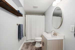 Full bathroom featuring shower / bath combination with curtain, toilet, and vanity