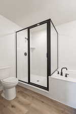 Bathroom featuring independent shower and bath, toilet, and hardwood / wood-style flooring