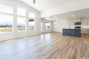 Unfurnished living room with light hardwood / wood-style floors, sink, a mountain view, and high vaulted ceiling