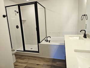 Full bathroom featuring double vanity, hardwood / wood-style flooring, independent shower and bath, and toilet