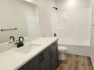 Full bathroom featuring hardwood / wood-style flooring, bathing tub / shower combination, toilet, and vanity