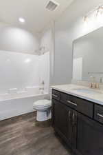 Full bathroom featuring bathing tub / shower combination, toilet, vanity, and wood-type flooring