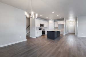 Kitchen with dark hardwood / wood-style flooring, white cabinets, a kitchen island with sink, and appliances with stainless steel finishes