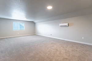 Basement with a textured ceiling, carpet, and a wall mounted air conditioner