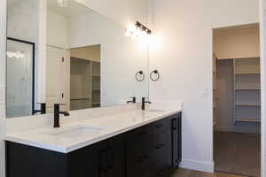 Bathroom with vanity, a shower with shower door, and wood-type flooring