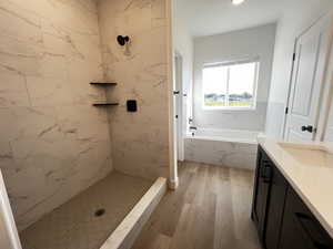 Bathroom with plus walk in shower, hardwood / wood-style floors, and vanity