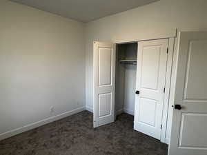 Unfurnished bedroom with dark carpet and a closet