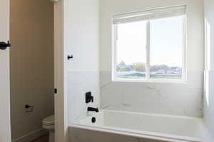 Bathroom with a relaxing tiled tub and toilet