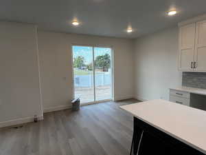 Kitchen with tasteful backsplash, light wood-type flooring, and white cabinets