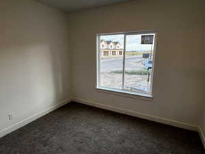 Unfurnished room with dark carpet and plenty of natural light