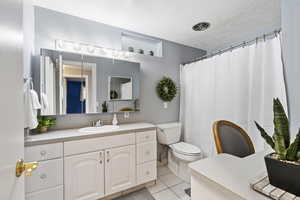 Bathroom with vanity, tile patterned flooring, toilet, and a textured ceiling