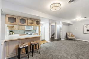 Kitchen featuring white appliances, sink, kitchen peninsula, a kitchen breakfast bar, and wood-type flooring