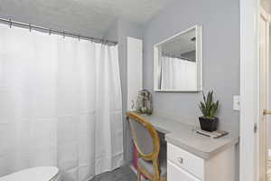 Bathroom with toilet, vanity, and a textured ceiling