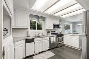 Kitchen featuring sink, white cabinetry, backsplash, and stainless steel appliances