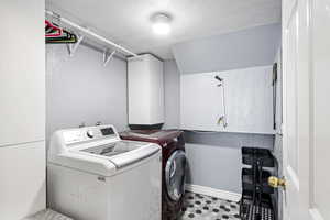 Laundry area featuring light tile patterned flooring, washing machine and dryer, and cabinets