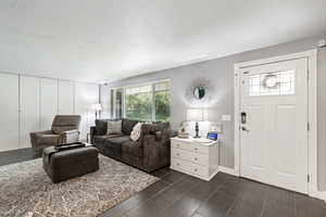 Living room featuring dark hardwood / wood-style flooring and a textured ceiling