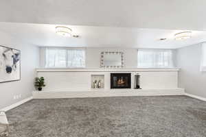 Unfurnished living room with carpet, a fireplace, and plenty of natural light