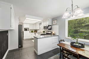 Kitchen featuring tasteful backsplash, stainless steel appliances, white cabinets, sink, and hanging light fixtures