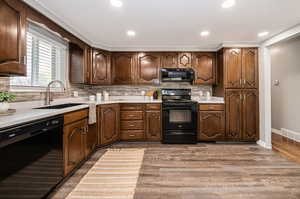 Kitchen featuring sink, black appliances, wood-type flooring, and tasteful backsplash