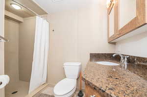 Bathroom with vanity, a shower with shower curtain, toilet, and tile patterned flooring