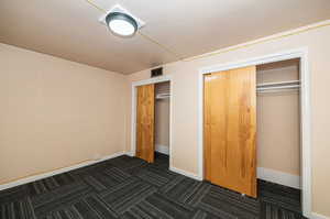 Unfurnished bedroom with dark colored carpet