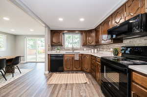 Kitchen featuring sink, wood-type flooring, black appliances, and backsplash