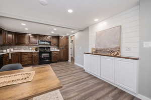 Kitchen featuring dark brown cabinetry, backsplash, black appliances, and light hardwood / wood-style floors