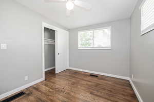 Unfurnished bedroom with a closet, ceiling fan, and dark wood-type flooring