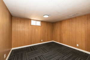 Unfurnished room featuring wood walls