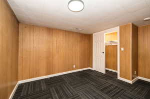 Unfurnished room featuring wooden walls