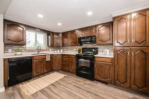 Kitchen featuring sink, black appliances, tasteful backsplash, and light wood-type flooring