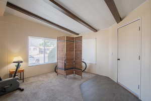 Living area with vaulted ceiling with beams and carpet floors