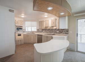 Kitchen with tasteful backsplash, stainless steel appliances, hardwood / wood-style floors, sink, and kitchen peninsula