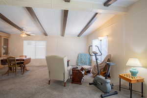 Living area featuring beamed ceiling, carpet floors, and ceiling fan