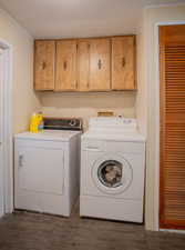 Laundry area featuring washing machine and dryer, dark hardwood / wood-style flooring, and cabinets