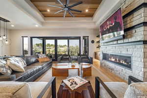 Living room featuring a fireplace, wood ceiling, light wood-type flooring, and a tray ceiling