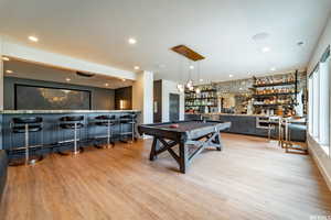 Playroom with light hardwood / wood-style floors, bar, and billiards