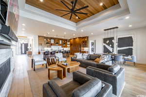 Living room with wooden ceiling, ceiling fan, a raised ceiling, and light hardwood / wood-style floors