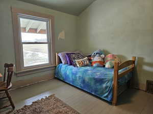 Bedroom with wood floors, vaulted ceiling