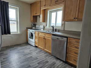 Kitchen featuring LVP flooring, sink, white gas range, and dishwasher