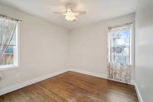 Unfurnished room with dark wood-type flooring and ceiling fan