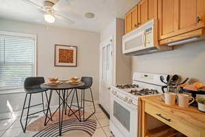 Kitchen featuring ceiling fan, light tile patterned floors, and white appliances