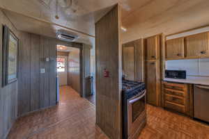 Kitchen featuring wooden walls, dark parquet floors, and appliances with stainless steel finishes