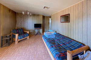 Bedroom featuring wood walls, light parquet floors, and an inviting chandelier