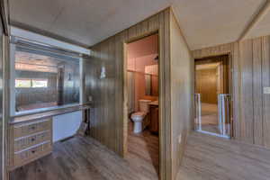 Bathroom with wood-type flooring, toilet, and wooden walls