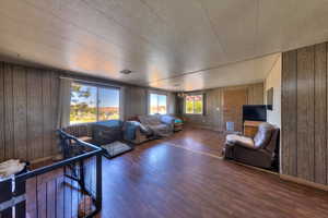 Living room with dark hardwood / wood-style flooring, a textured ceiling, and wooden walls