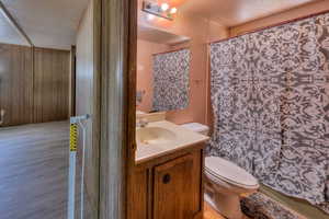 Bathroom featuring vanity, hardwood / wood-style flooring, toilet, and wood walls