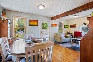 Dining room with a textured ceiling, beam ceiling, and hardwood / wood-style floors